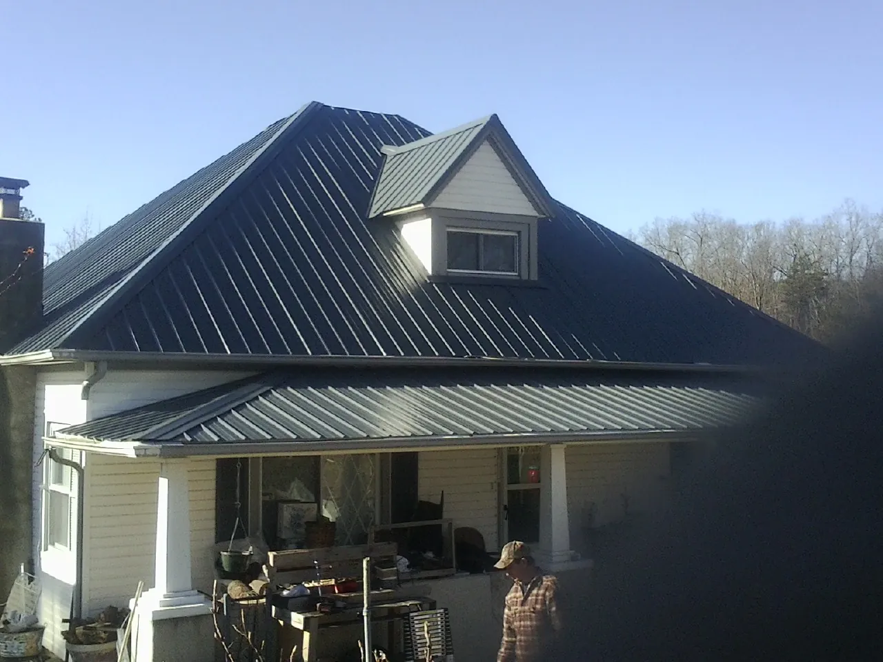 Dark blue standing seam metal roof with a dormer above a front porch in Bethel