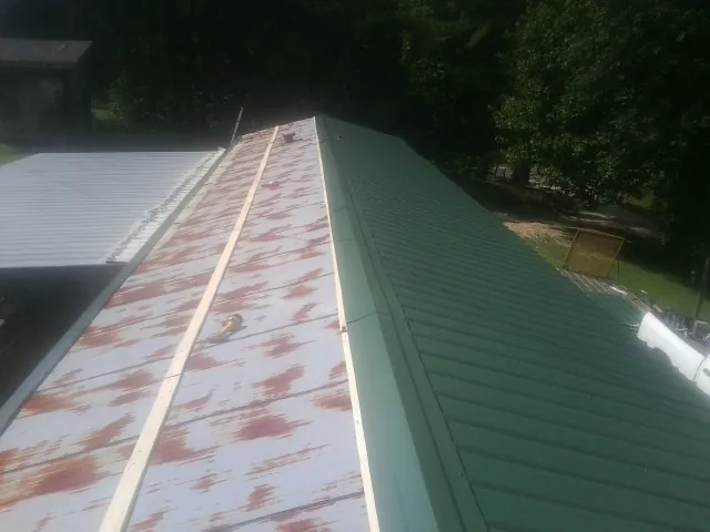 Old rusted panels beside newly installed green metal roofing — Wind Damage Roof Repair by Roofing Brothers in Bethel